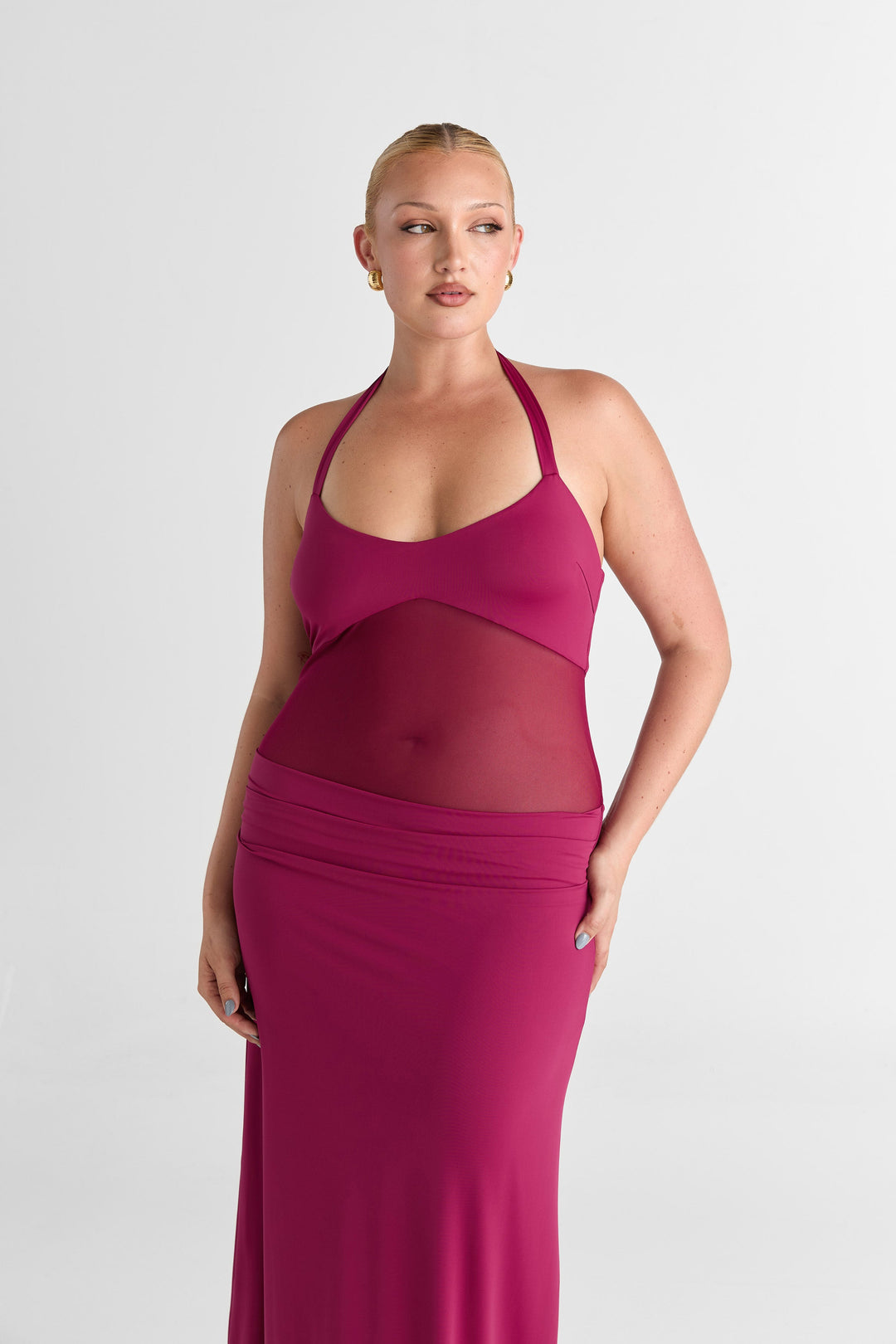 Woman wearing a pink dress with mesh panels on a white background