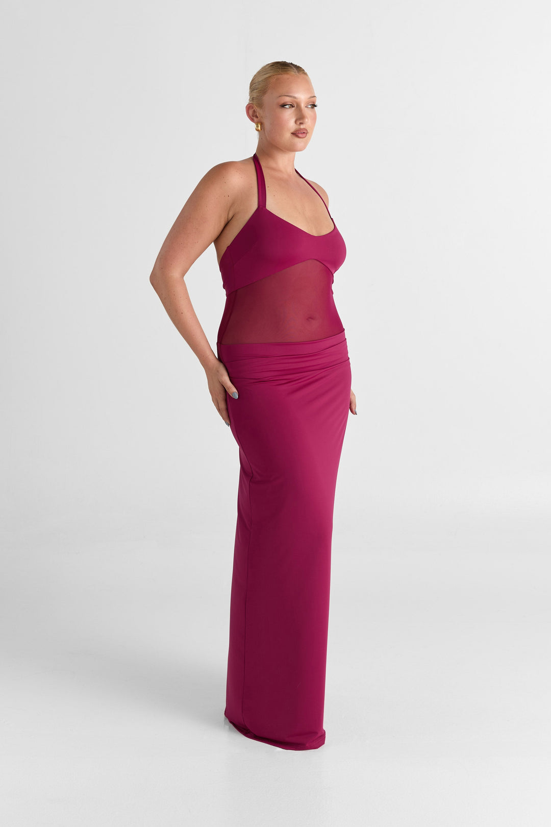Woman wearing a long magenta dress against a white background