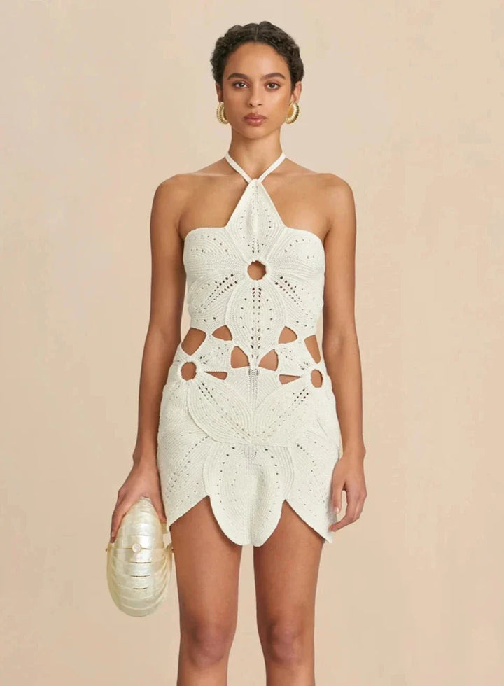Model wearing ivory crochet cutout mini dress with halter neckline and floral pattern, perfect for summer beachwear and resort fashion