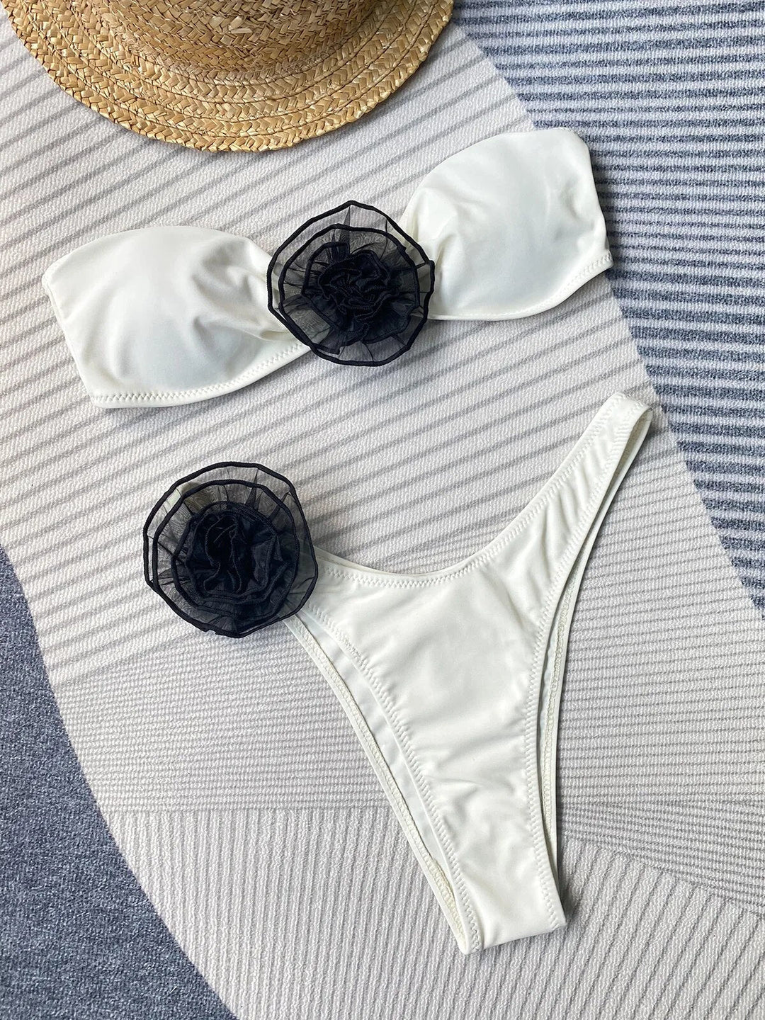 A woman wearing a black bikini with white floral details on the top.