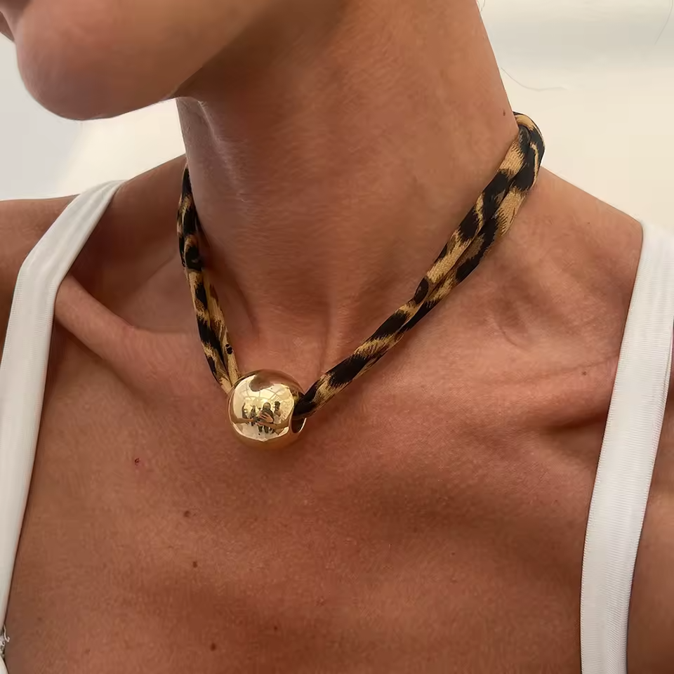 Leopard print necklace with a gold pendant worn by a person
