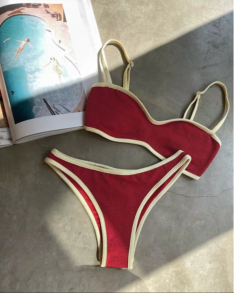 Red bikini with beige trim on a gray surface next to an open magazine.