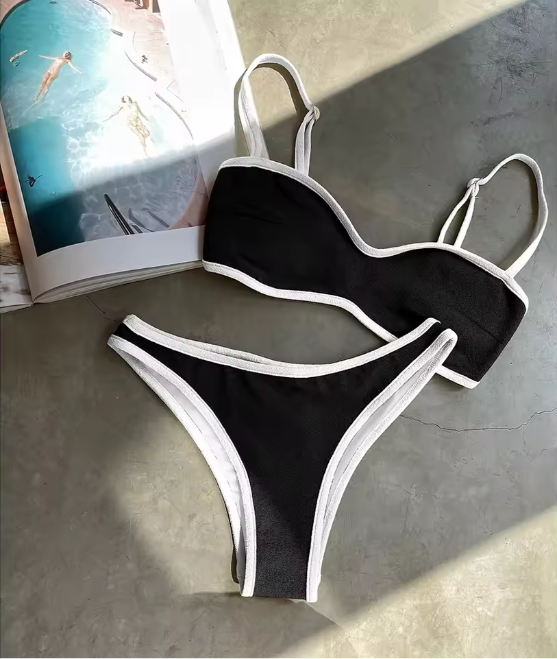 Black bikini with white straps on a gray surface