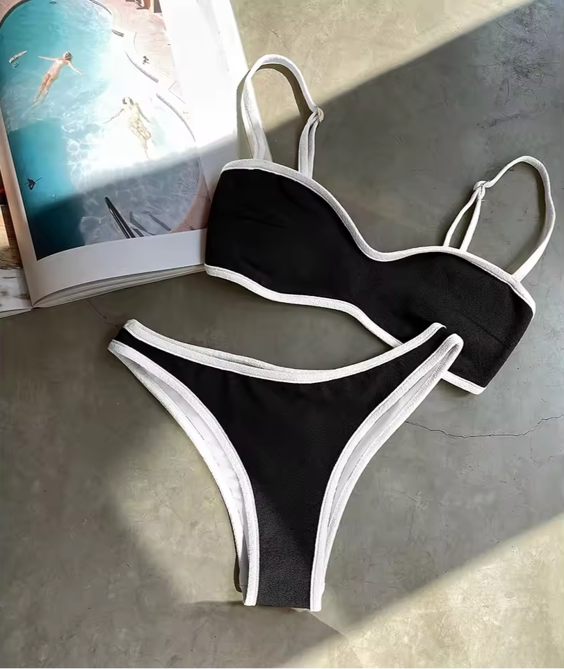 Black bikini with white straps on a gray surface